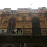Foto 13. Questo �buco� si trova accanto a un basso edificio fatiscente, di colore ocra, che per� conserva ancora un particolare rilievo: spicca centrale la figura di un bambino, circondato da alcune foglie di quello che sembra alloro. Il tutto � sovrastato da una singolare cornice merlata